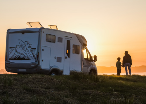 vrouw en kind met camper kijken naar ondergaande zon